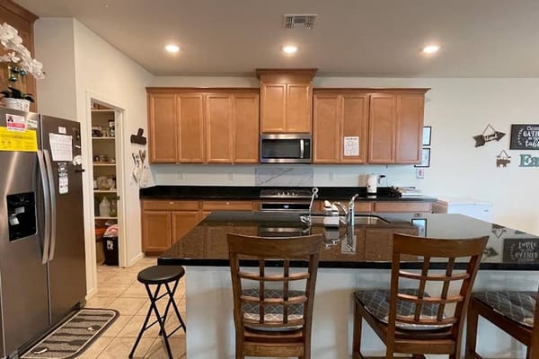 A spacious kitchen with wooden cabinets and black countertops.