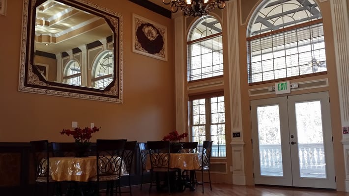 Dining area with tables and large windows in Golden Age Personal Care Home.