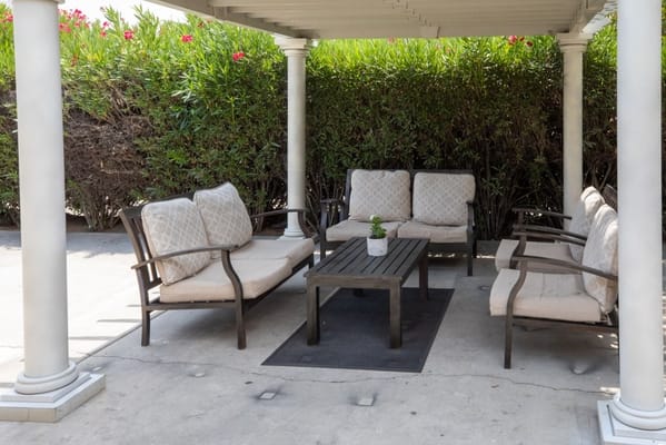Outdoor seating area under a patio with greenery