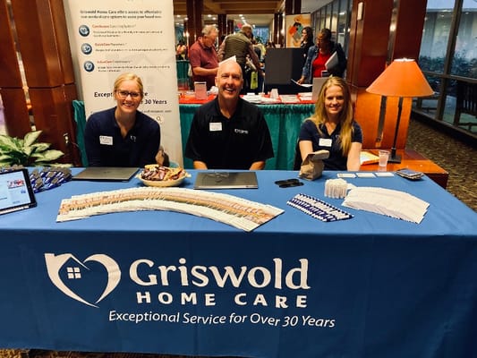 Staff members at a promotional table with information and snacks