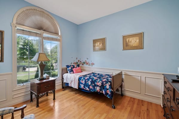 A cozy bedroom with floral bedding and large windows