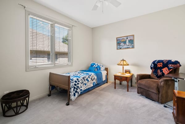 Bright and cozy bedroom with floral bedding and a comfortable chair.