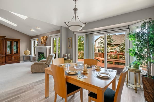Bright dining area with a wooden table and chairs overlooking a deck