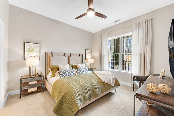 A well-decorated bedroom with a green blanket and large windows