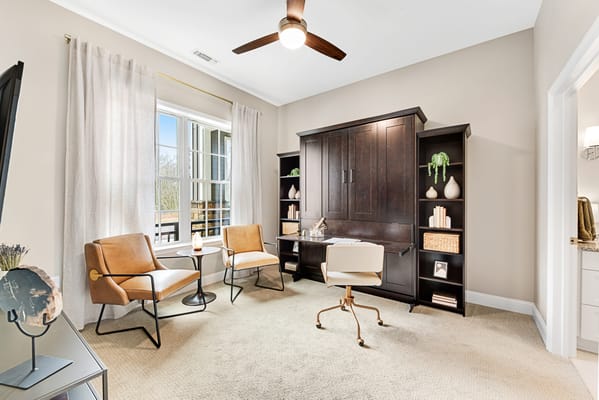 A study room with two chairs, a desk, and large windows
