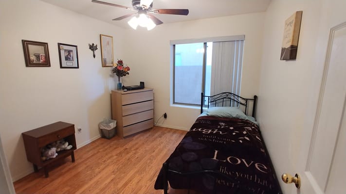 A cozy bedroom featuring a bed, dresser, and decorative items.