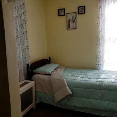 A comfortable bedroom featuring a bed with a blue comforter and floral curtains.