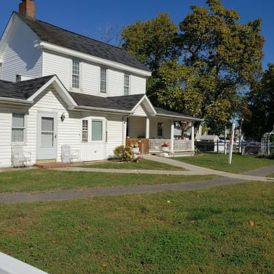 A white house with a porch and landscaped yard at Locust Lodge.