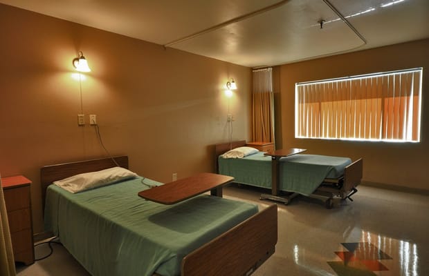 A shared resident room with two beds and bedside tables