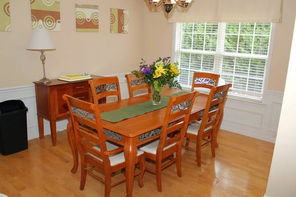 Bright dining room with a large wooden table and flowers