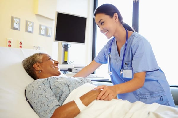 A nurse interacting with a smiling resident in a care setting
