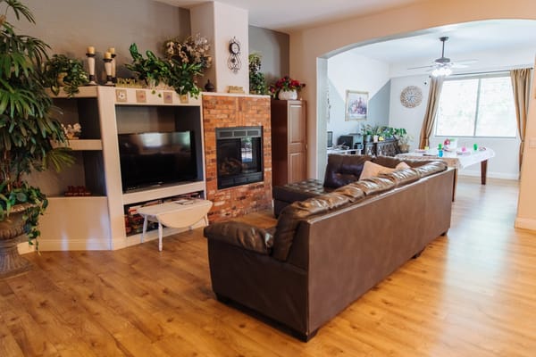Living room with a brown sofa, TV, and a view to the dining area