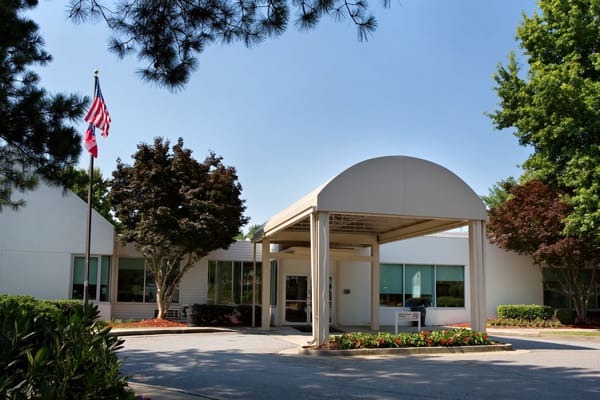 Entrance view of Northside Gwinnett Extended Care Center with flags and landscaping.