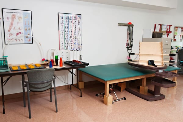 Well-equipped therapy room with tables and rehabilitation tools.