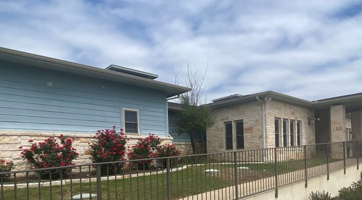 Exterior shot of Provident Memory Care with pink roses and blue sky