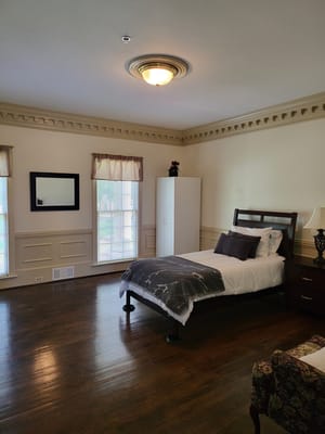 Cozy bedroom with a bed, nightstand, and large windows
