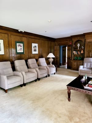 A cozy lounge area featuring comfortable armchairs and a wooden bookshelf.