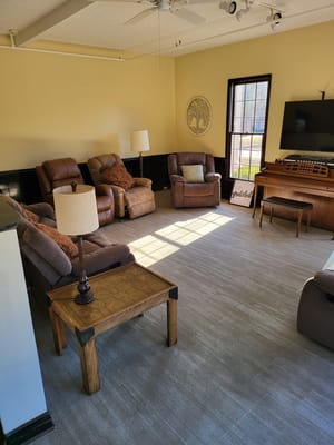 A cozy living room with recliner chairs, a wooden table, and a TV.