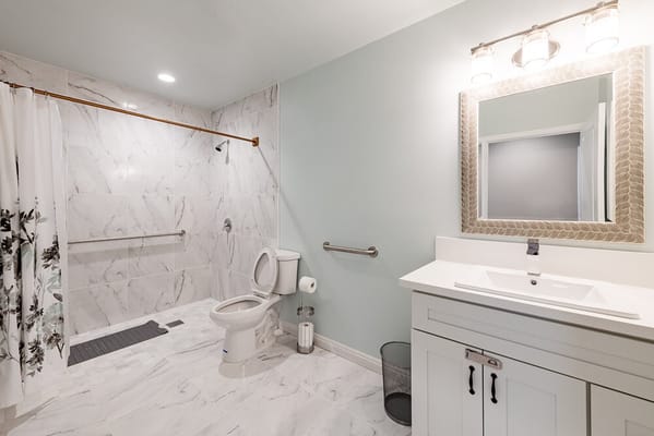 Spacious bathroom with marble walls and walk-in shower