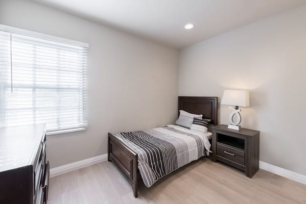 Simple bedroom with a bed, dresser, and lamp.