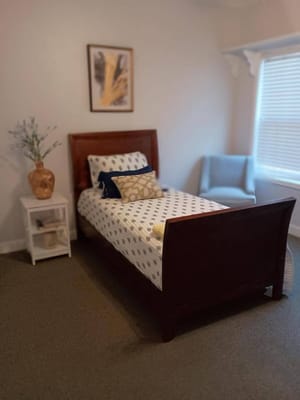 A cozy bedroom with a bed, decorative pillows, and a chair.