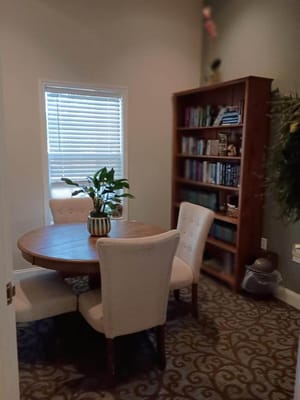 A round wooden table with four chairs and a plant in a cozy room.