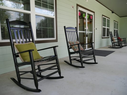 Two black rocking chairs with cushions on a porch