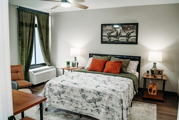 A cozy bedroom featuring a bed with decorative pillows, bedside tables, and curtains.