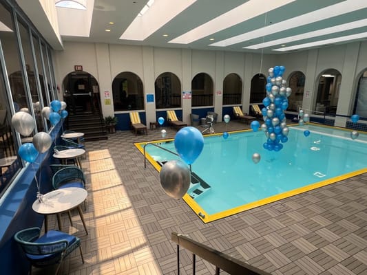Indoor pool area decorated with blue and silver balloons