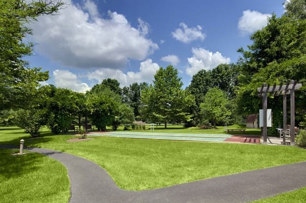 Lush green garden area with a pool and walking path