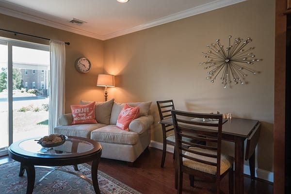 Comfortable living room with a sofa, dining table, and large windows.