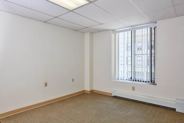 An empty room with a window featuring blinds.