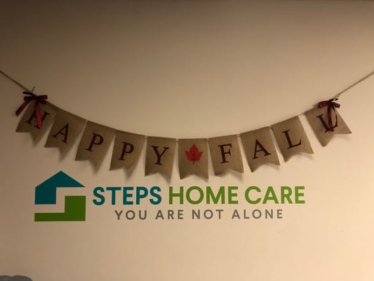 A burlap banner reading 'Happy Fall' with a leaf accent next to the STEPS Home Care logo