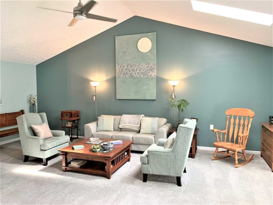 A cozy living room with teal walls, a sofa, and armchairs.