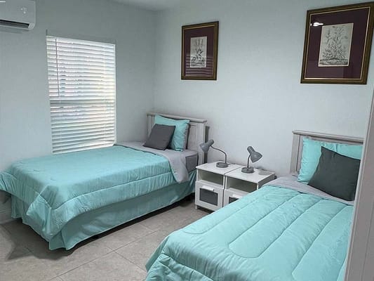 Two twin beds in a brightly lit room with light blue bedding.