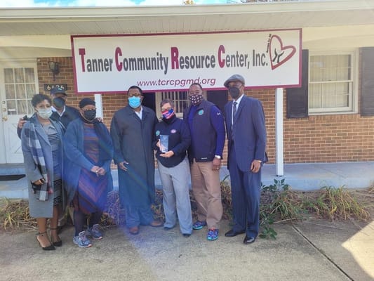 A group of individuals standing in front of the Tanner Community Resource Center sign.