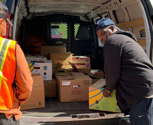 Volunteers unloading boxes of food from a delivery van