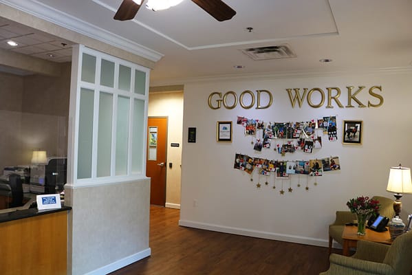 Interior view showcasing a welcoming lobby with 'GOOD WORKS' sign and photo wall.