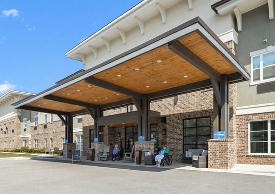 Entrance of The Addison of Gwinnett Park with residents relaxing outside.