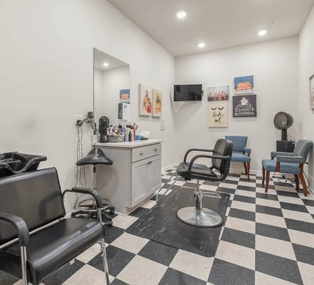 Interior of the salon featuring chairs and a mirror.