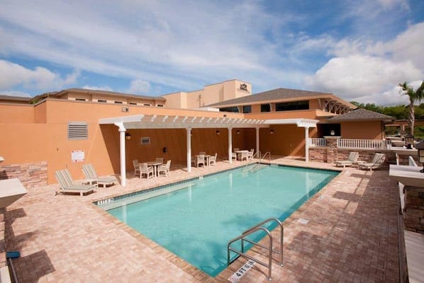 A pool area with lounge chairs and sunny sky
