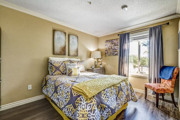 Well-decorated bedroom with a floral bedspread and window view.
