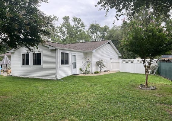 Exterior view of a white building with a grassy yard and trees