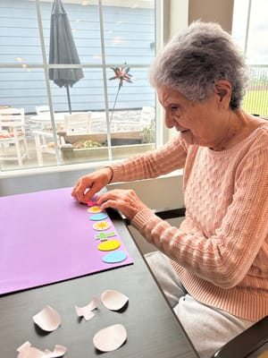 A resident crafting with colored paper at a table