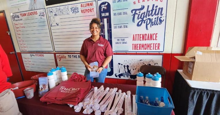 Staff member at TruCare Home Care Services booth with promotional materials