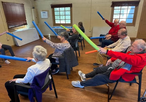 Seniors participating in an exercise class with foam pool noodles
