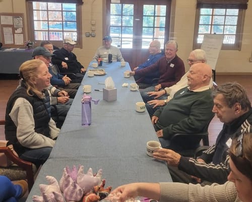 Seniors gathered around a table chatting and enjoying drinks.