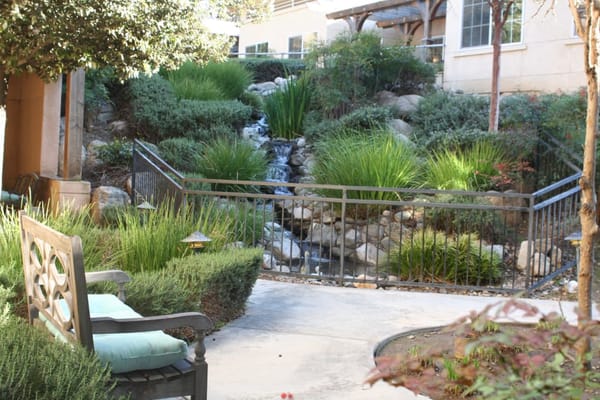 A landscaped garden with a small stream and seating area.