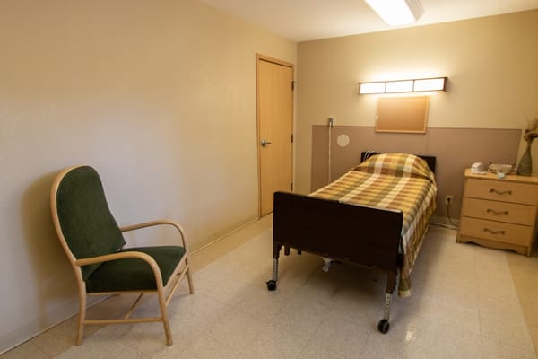 A cozy room featuring a bed, a chair, and a dresser.