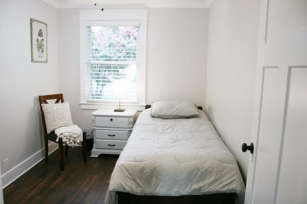 Brightly lit private resident room with a bed and chair